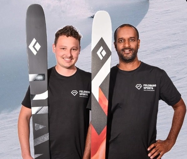 Zwei Mitarbeiter von Feldberg Sports präsentieren stolz moderne Wintersport-Ausrüstung.