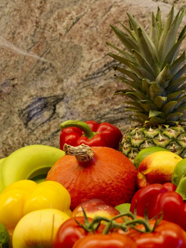 Eine bunte Auswahl an frischem Obst und Gemüse, appetitlich auf einer Holzplatte angerichtet.