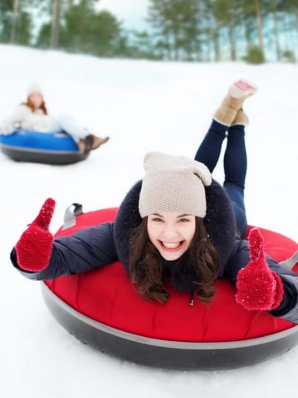 Ein Kind rutscht voller Freude beim Snowtubing im verschneiten Hochschwarzwald einen Hang hinunter.