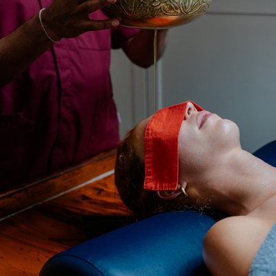 Therapeut gießt behutsam warmes Öl bei einer Ayurveda-Behandlung im Hotel Vier Jahreszeiten am Schluchsee aus einer Schale.