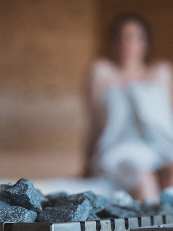 Eine Frau genießt die wohlige Wärme während eines Saunagangs in der Wellnesslandschaft des Hotels.