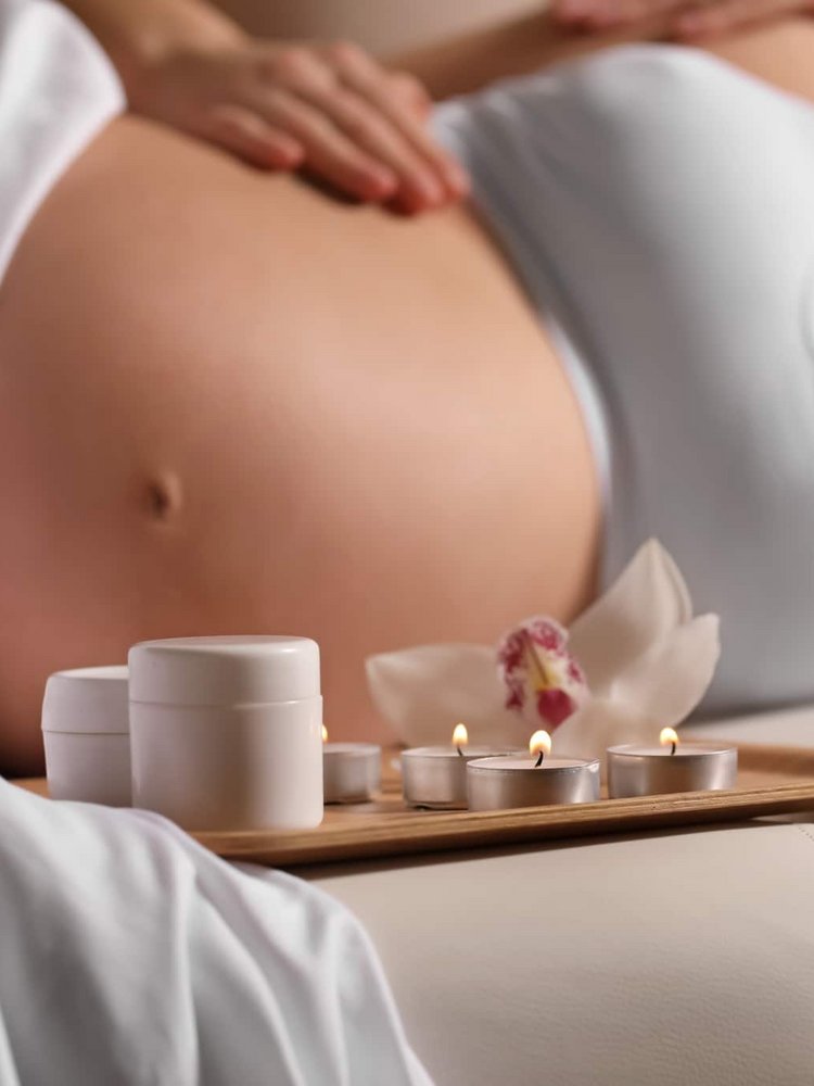 Eine schwangere Frau entspannt in Seitenlage neben einem Tablett mit Wellness-Utensilien im Hotel Vier Jahreszeiten im Schwarzwald.