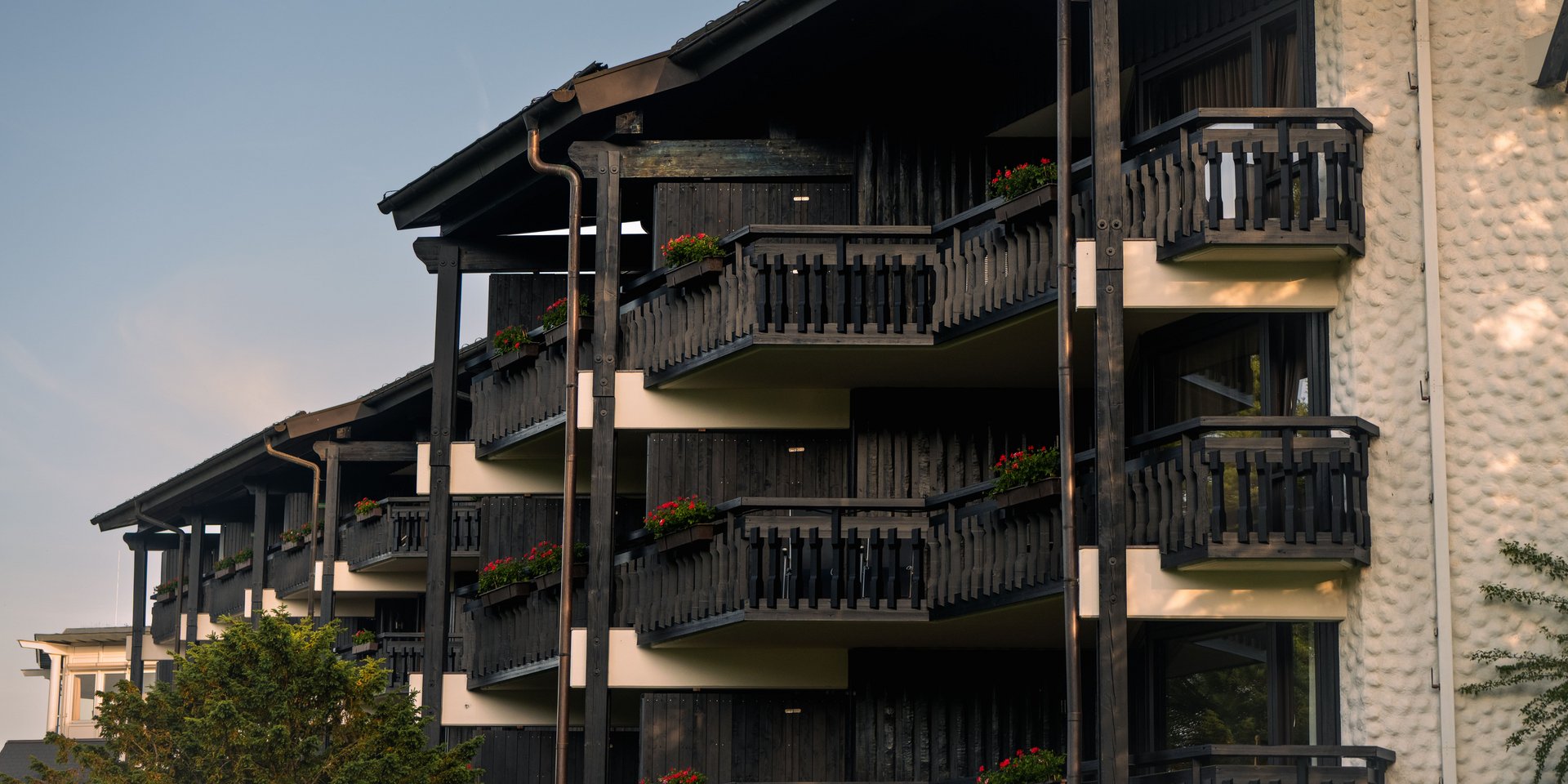 Außenansicht der dunklen Holzfassade mit den charakteristischen Balkonen des Hotels.