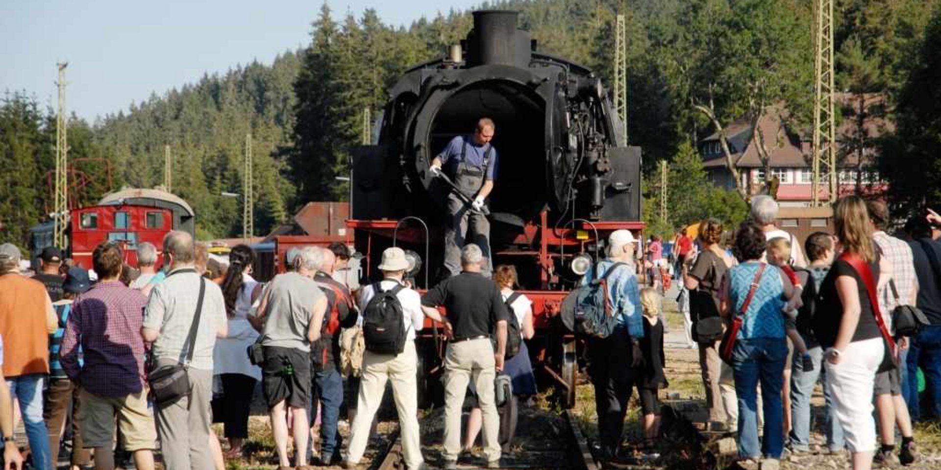 Eine große Personengruppe bei einer Besichtigung der historischen Dampflok im Schwarzwald.