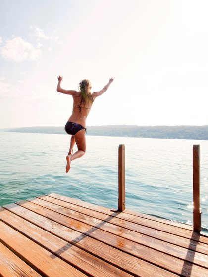 Frau springt vom Steg in einen See
