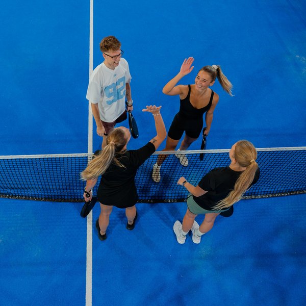 Blick von oben auf eine Padel-Gruppe beim gemeinsamen Abklatschen auf dem Spielfeld.