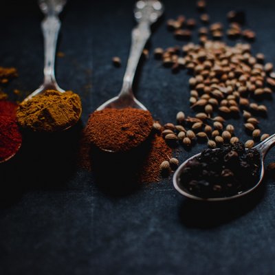 Eine Auswahl farbenfroher Gewürze auf silbernen Löffeln für die gesunde Vitalküche.