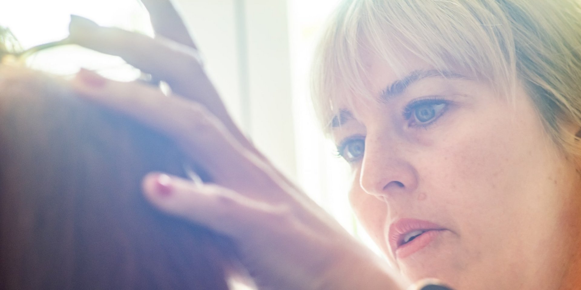 Eine Kosmetikerin trägt professionell Make-up bei einer Kundin im Wellnessbereich auf.