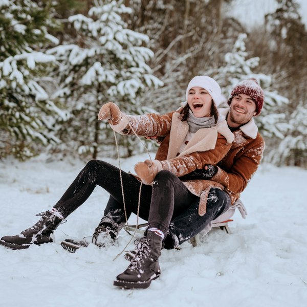 Paar im Schnee beim Schlittenfahren