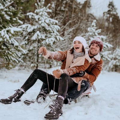 Paar im Schnee beim Schlittenfahren