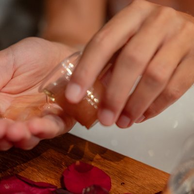 Nahaufnahme einer Hand, die pflegendes Badeöl in das warme Wasser einer Wanne im Hotel Vier Jahreszeiten im Schwarzwald gießt.