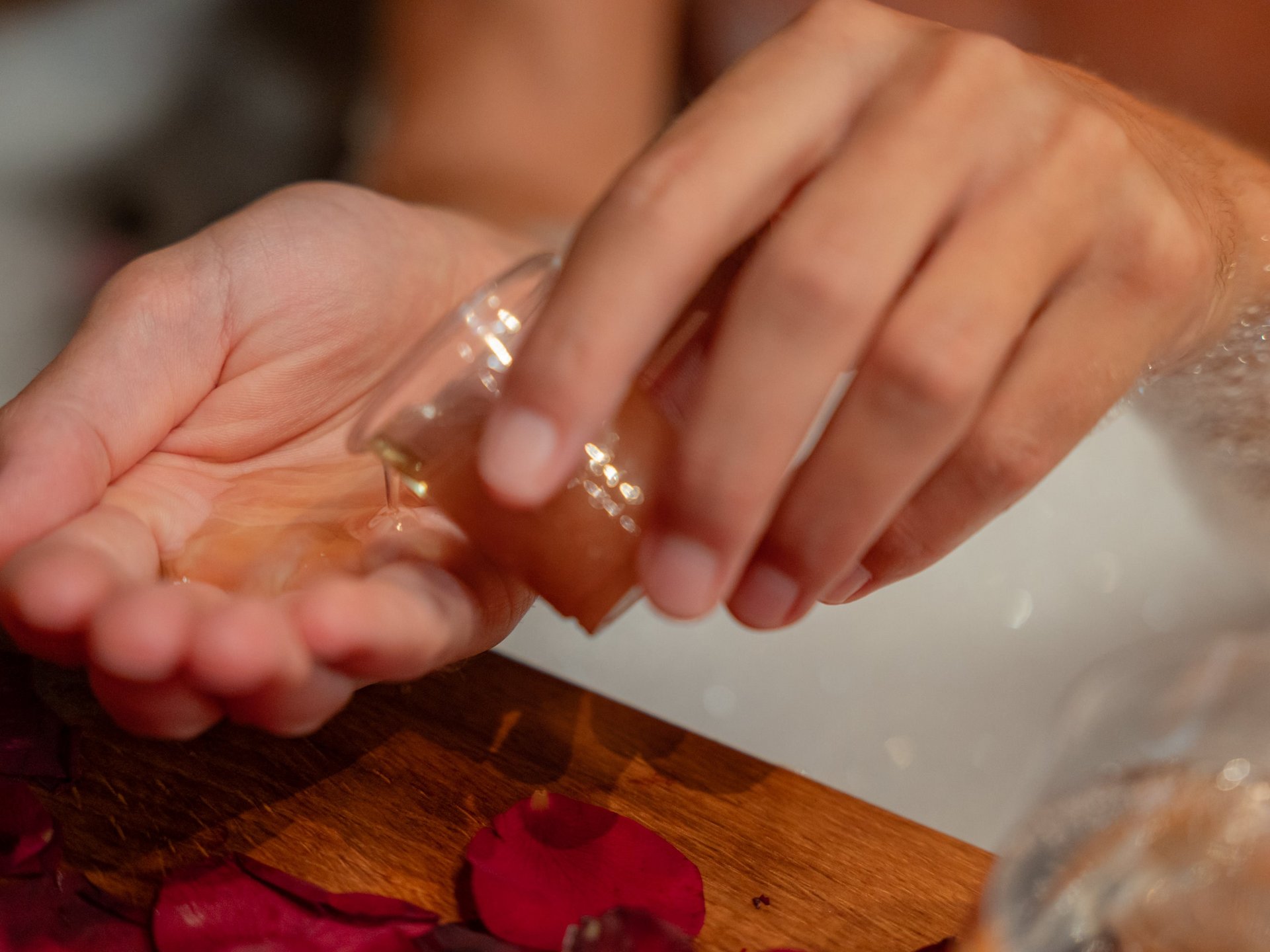 Nahaufnahme einer Hand, die pflegendes Badeöl in das warme Wasser einer Wanne im Hotel Vier Jahreszeiten im Schwarzwald gießt.