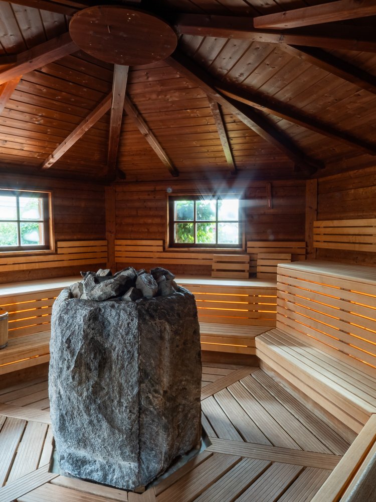 Innenansicht einer großzügigen Holzsauna mit zentralem Saunaofen im Schwarzwald-Stil.