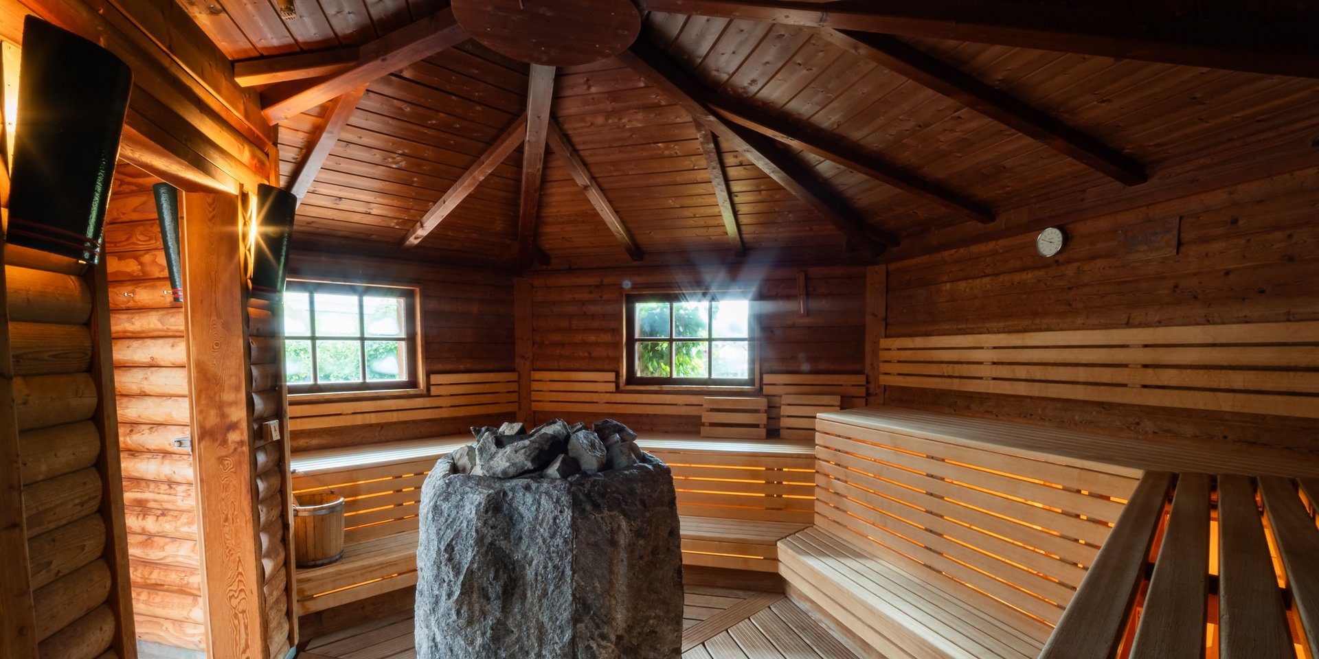 Innenansicht einer großzügigen Holzsauna mit zentralem Saunaofen im Schwarzwald-Stil.