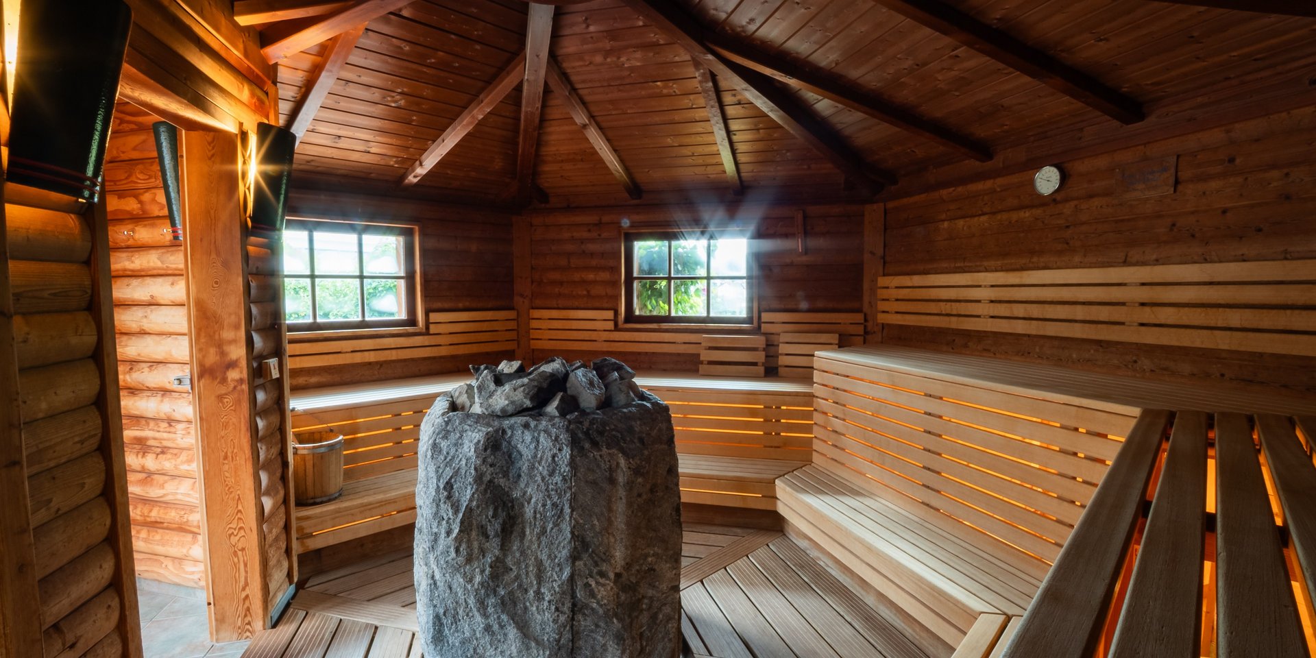 Innenansicht einer großzügigen Holzsauna mit zentralem Saunaofen im Schwarzwald-Stil.