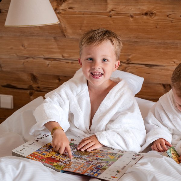 Kind sitzt mit Bademantel im Bett