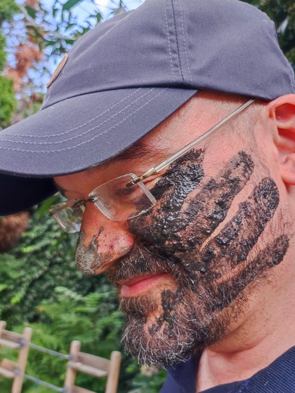 Porträt von einem Teammitglied des Hotels Vier Jahreszeiten am Schluchsee im Freien mit einem dunklen Handabdruck auf der Wange.