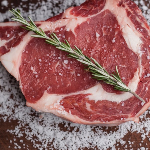 Ein frisch gebratenes, saftiges Steak auf einem Holzbrett, garniert mit Meersalz und Rosmarin.