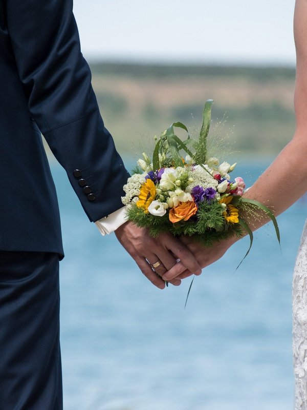 Ein Brautpaar geht Hand in Hand am Ufer des Schluchsees spazieren.