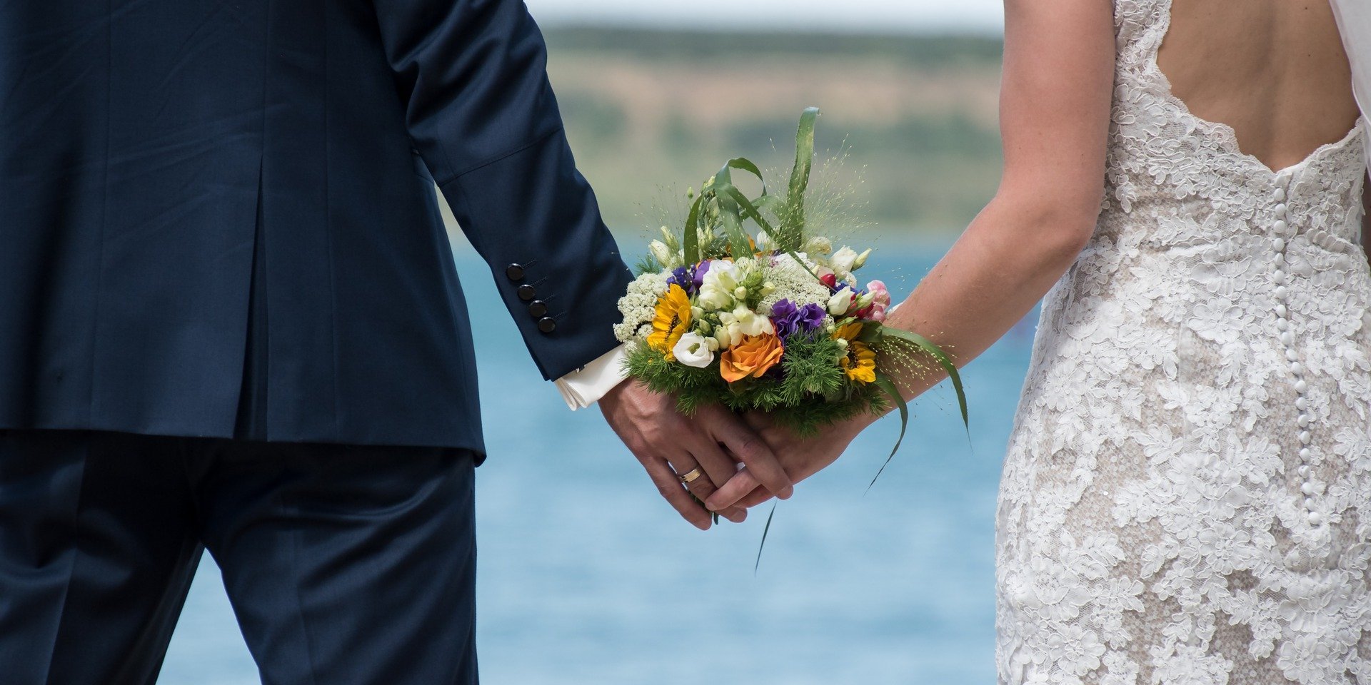 Ein Brautpaar geht Hand in Hand am Ufer des Schluchsees spazieren.