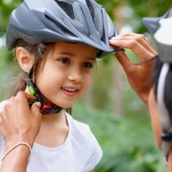 Eine Mutter hilft ihrem Kind beim Aufsetzen des Fahrradhelms vor einer Tour im Schwarzwald.