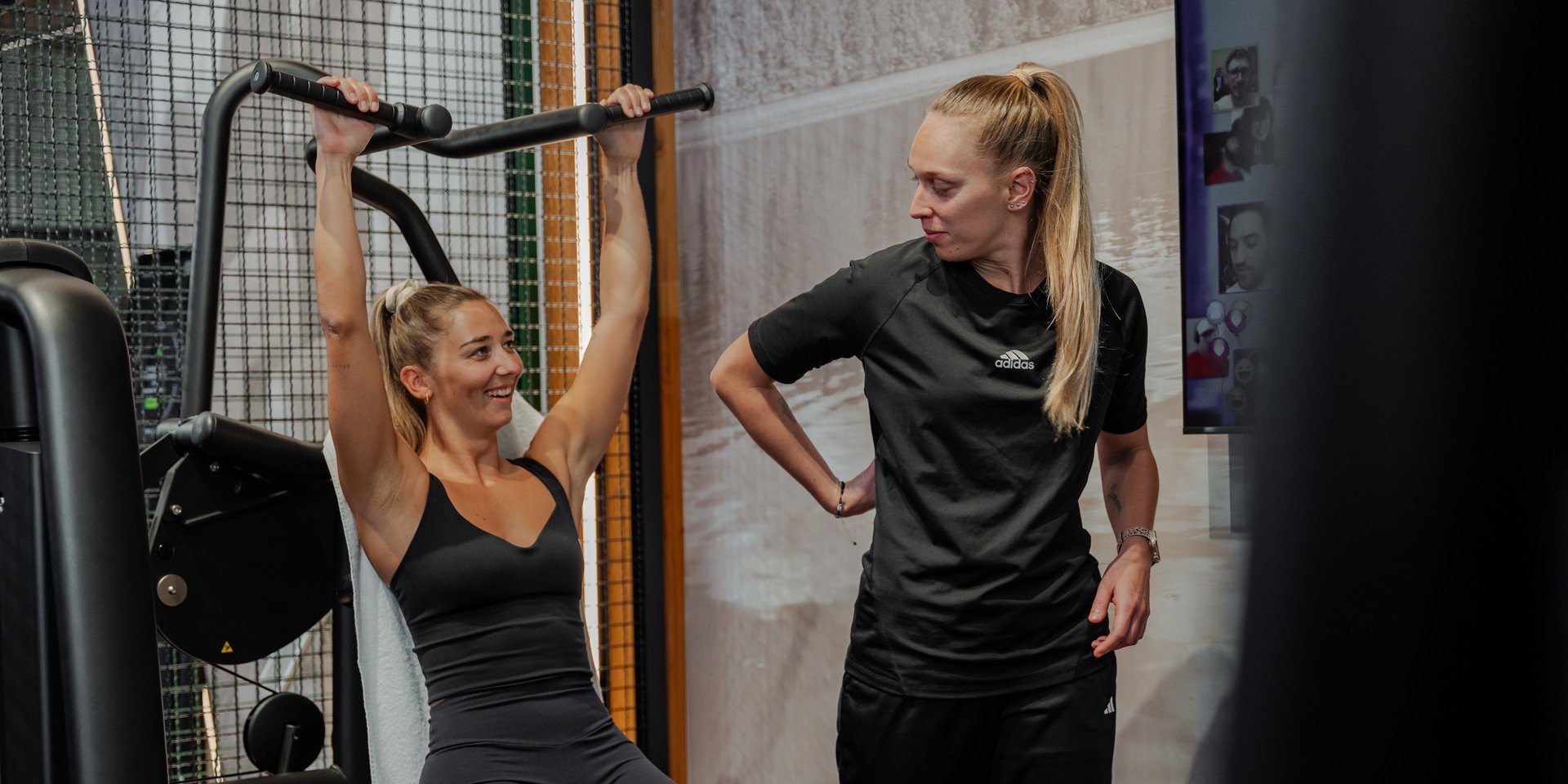 Krafttraining unter Anleitung: Eine Frau führt Latzug-Übungen im Gym aus.