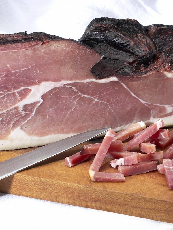 Am Stück servierter original Schwarzwälder Schinken auf einem Holzbrett.