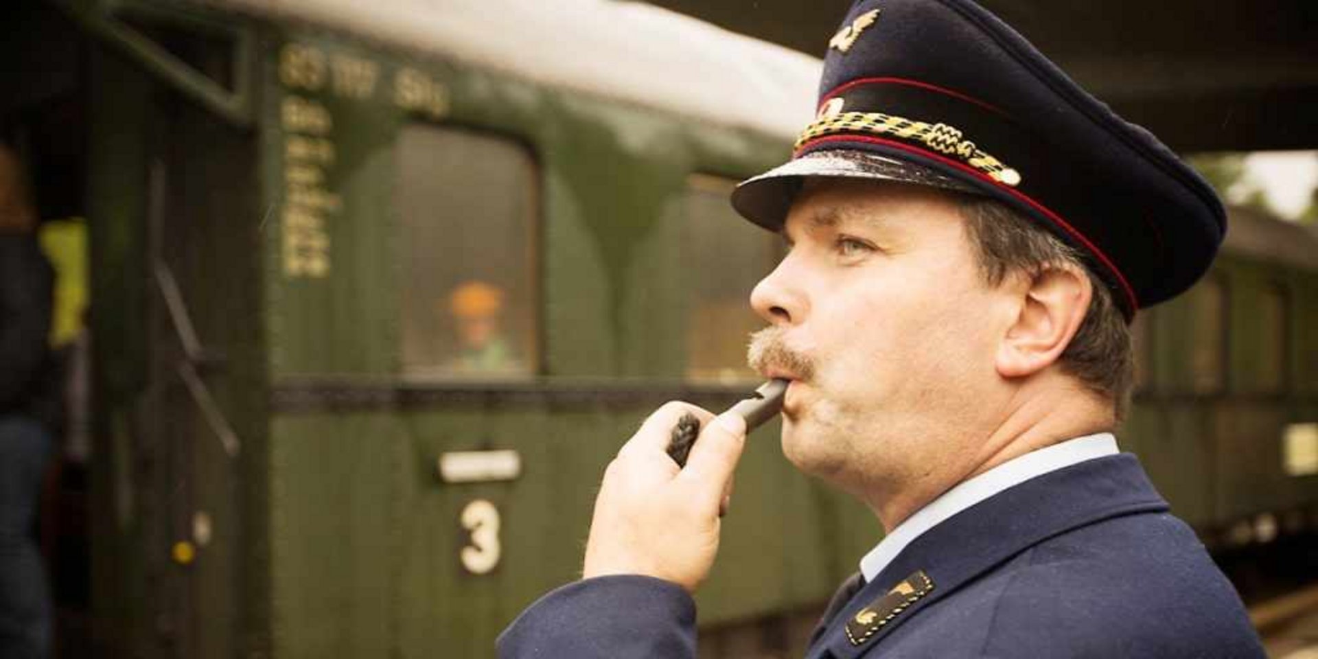 Ein Zugbegleiter in historischer Uniform gibt das Abfahrtssignal für die Schwarzwald-Museumsbahn.