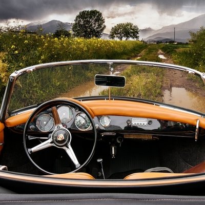 Blick auf das Armaturenbrett eines klassischen Oldtimers während einer Fahrt durch die Natur.