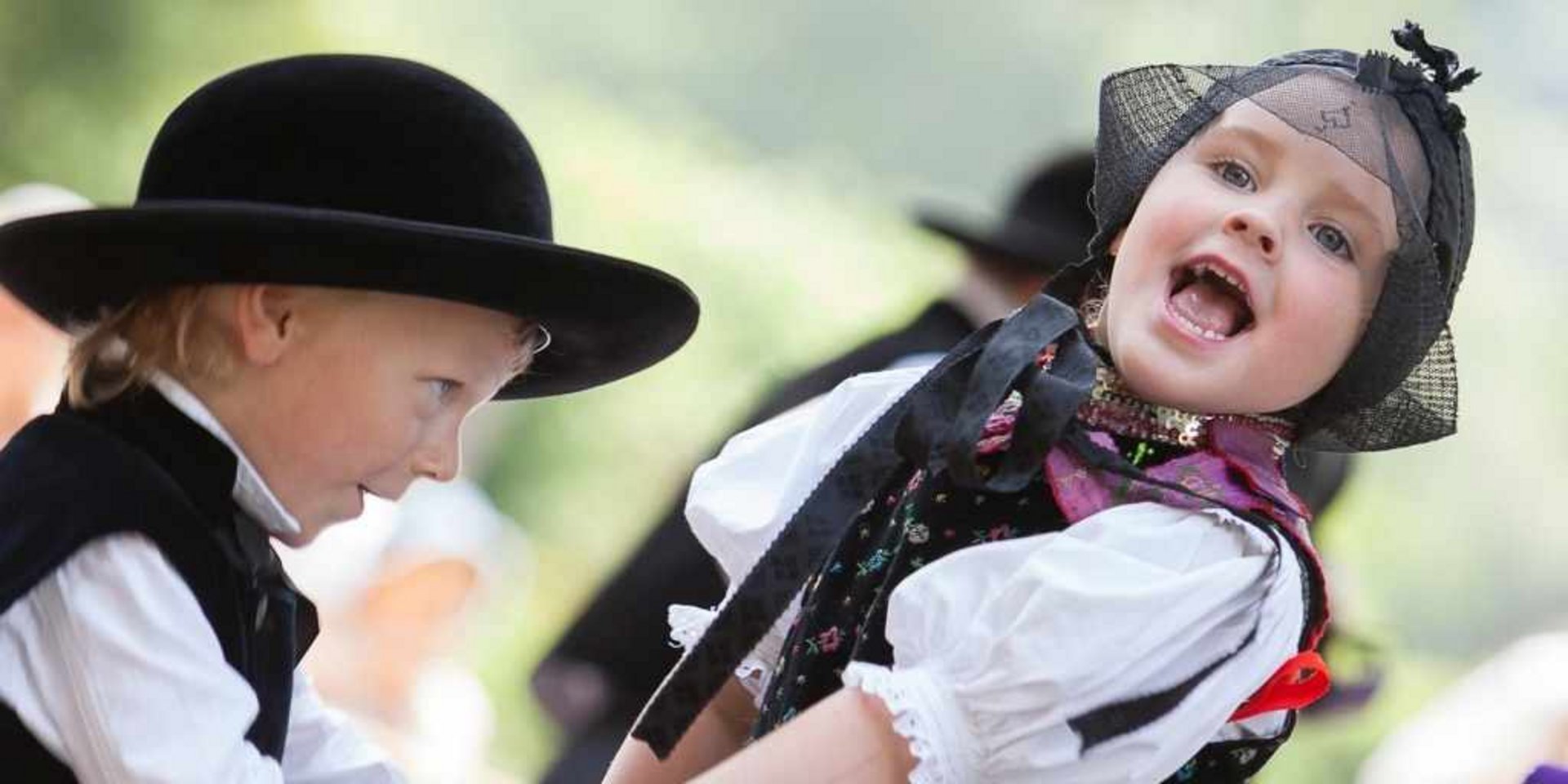 Kinder in traditioneller Tracht beim Tanzen im Freilichtmuseum – Brauchtumspflege.