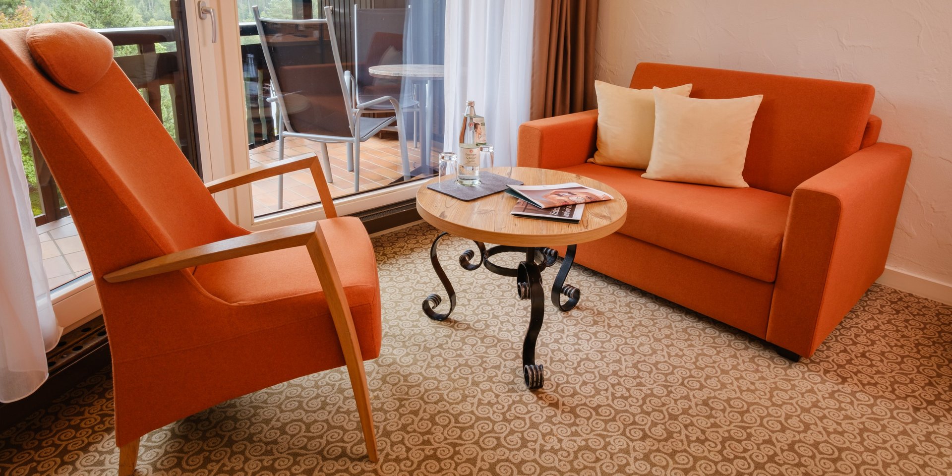 Wohnbereich mit orangefarbenem Sessel und Sofa für entspannte Stunden im Schwarzwald.