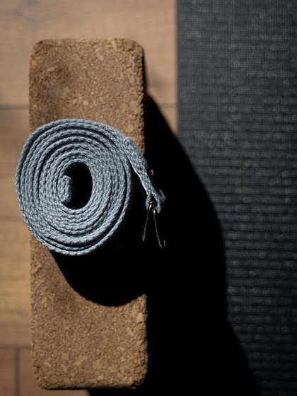 Yoga Block auf dem ein Strechband liegt, neben einer Matte