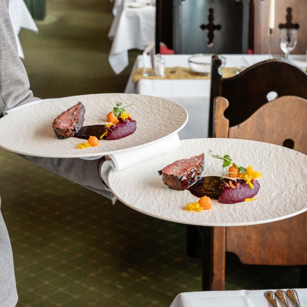 Servicemitarbeiter tragen gleichzeitig mehrere Teller durch das gut besuchte Panorama-Restaurant.