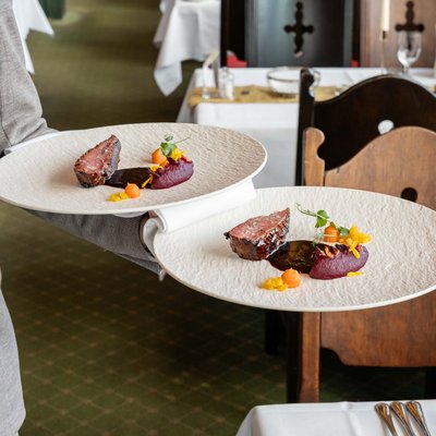 Servicemitarbeiter tragen gleichzeitig mehrere Teller durch das gut besuchte Panorama-Restaurant.