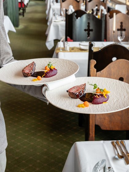Servicemitarbeiter tragen gleichzeitig mehrere Teller durch das gut besuchte Panorama-Restaurant.