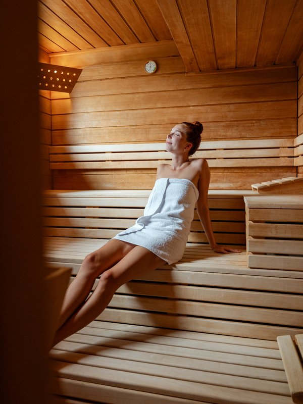 Stimmungsvolles Porträt einer Frau beim Ausruhen in der sanft beleuchteten Sauna des Hotels.