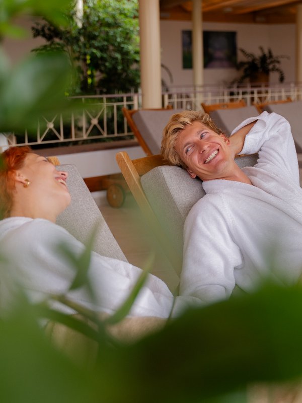Zwei Gäste entspannen in flauschigen Bademänteln auf bequemen Liegen im Spa des Hotels Vier Jahreszeiten im Schwarzwald.