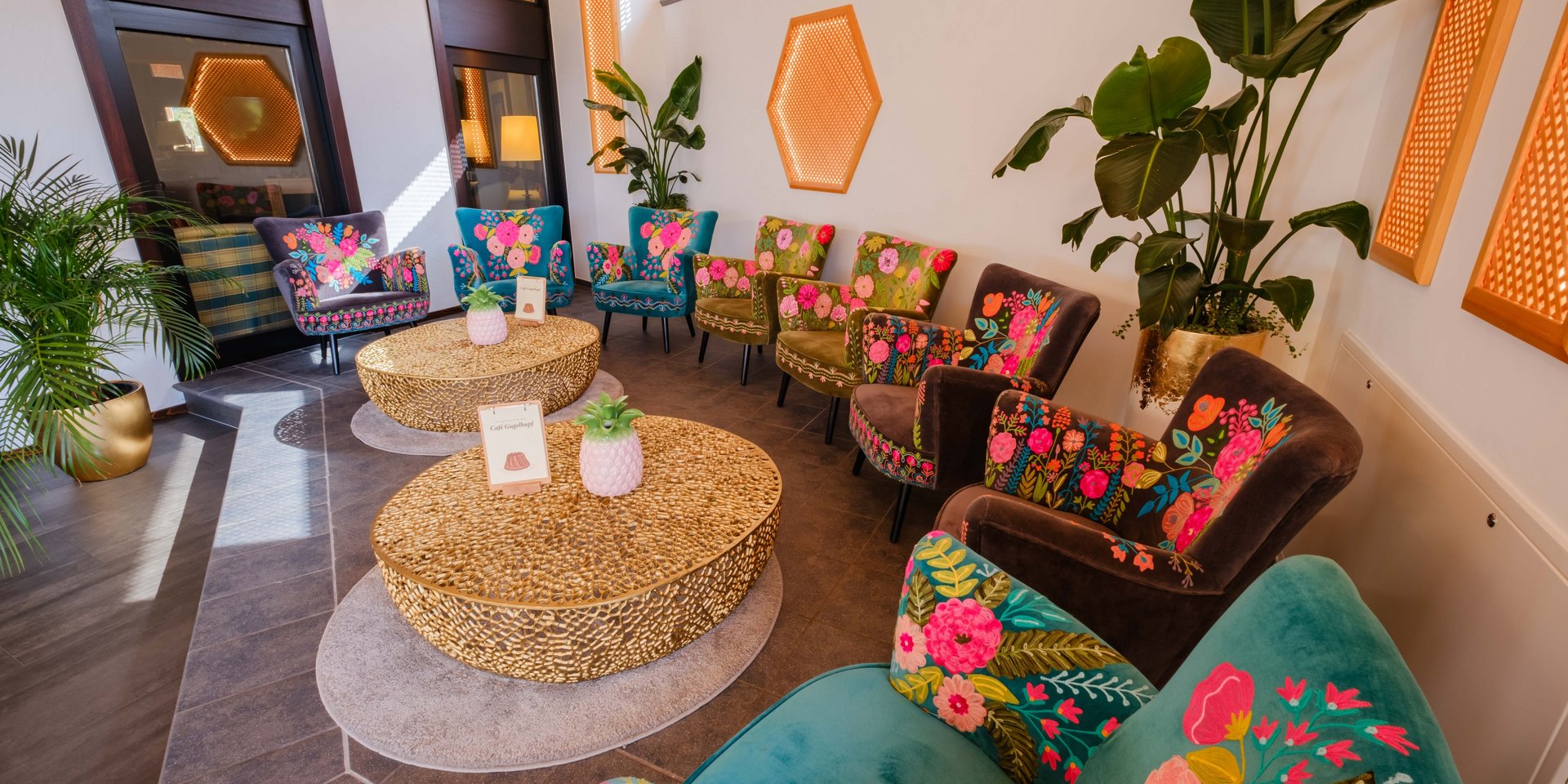 Farbenfrohe Lounge-Sessel und rustikale Holztische im lichtdurchfluteten Innenbereich des Hotels Vier Jahreszeiten am Schluchsee.