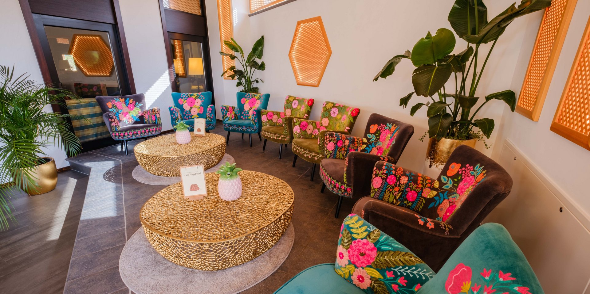 Farbenfrohe Lounge-Sessel und rustikale Holztische im lichtdurchfluteten Innenbereich des Hotels Vier Jahreszeiten am Schluchsee.