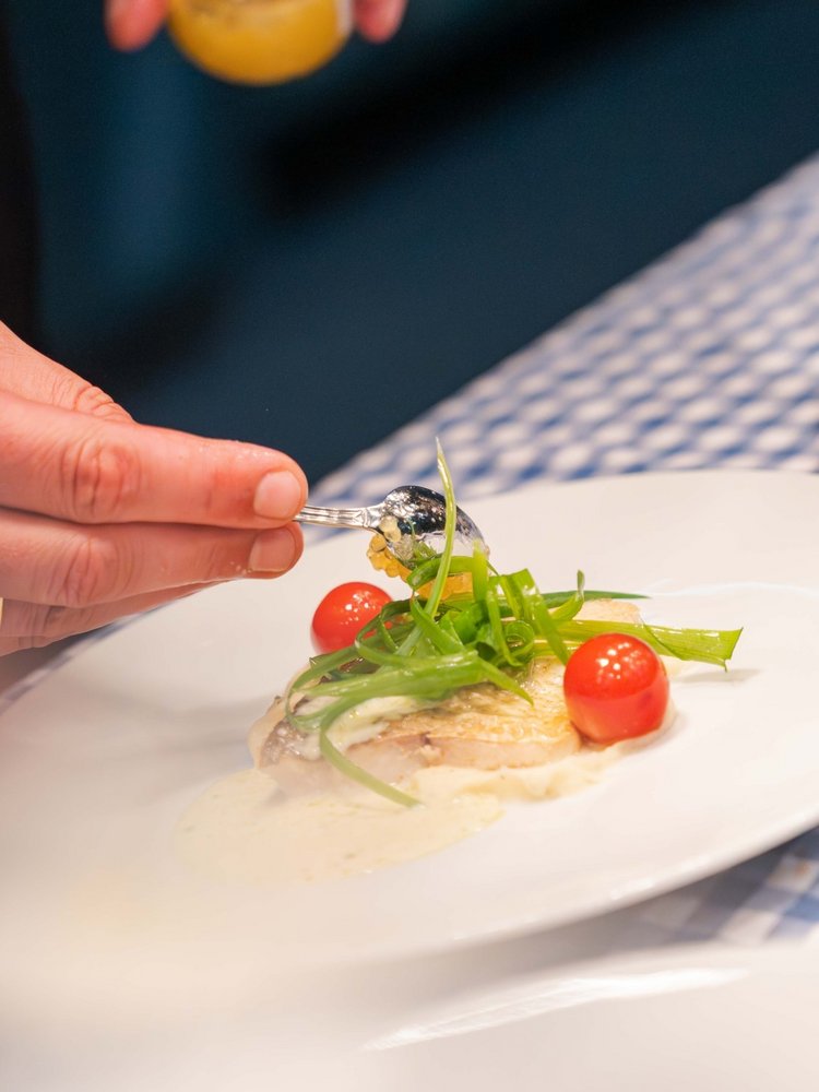 Ein Koch richtet mit einer Pinzette filigran eine feine Speise im Hotel Vier Jahreszeiten am Schluchsee an.