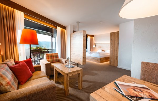 Wohnzimmer mit warmem Lichtkonzept und Blick in den Schlafbereich im Hotel Vier Jahreszeiten am Schluchsee.