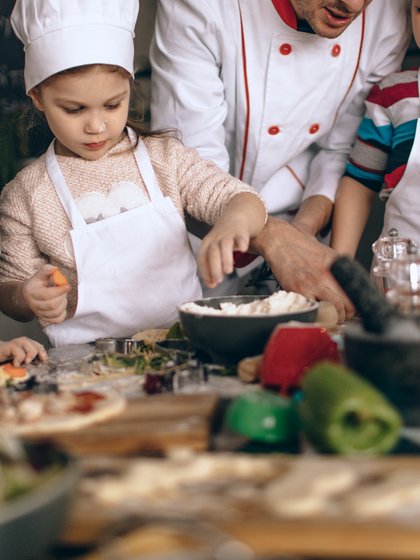 Kinder kochen im Vordergrund sind verschiedene Utensilien und Zutaten