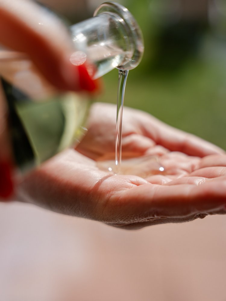 Nahaufnahme von Massageöl, das in die Handflächen einer Masseurin im Hotel Vier Jahreszeiten im Schwarzwald fließt.