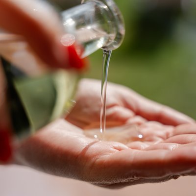 Nahaufnahme von Massageöl, das in die Handflächen einer Masseurin im Hotel Vier Jahreszeiten im Schwarzwald fließt.