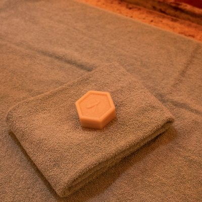 Detailaufnahme einer dekorierten Massagebank mit Handtuch und Aroma-Stein im Spa-Bereich.