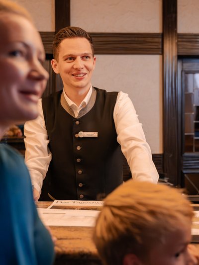 Herzlicher Empfang durch einen Mitarbeiter an der Hotelrezeption im Schwarzwald.
