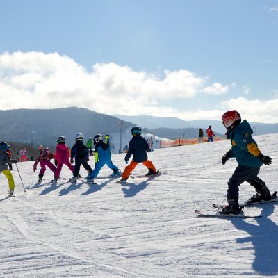 Skikurs für Kinder: Gemeinsame Abfahrt in der Gruppe auf einem gut präparierten Hang.