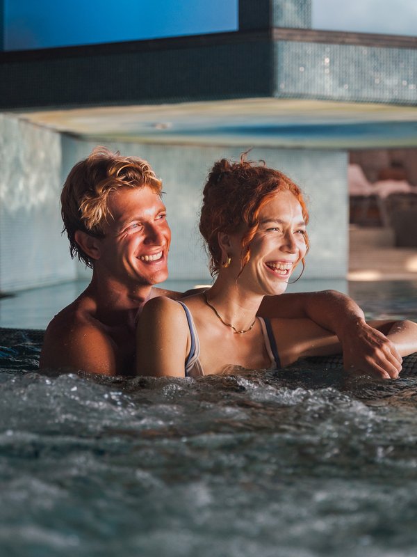 Ein Paar genießt entspannt die Massagedüsen im beheizten Whirlpool des Hotels Vier Jahreszeiten.