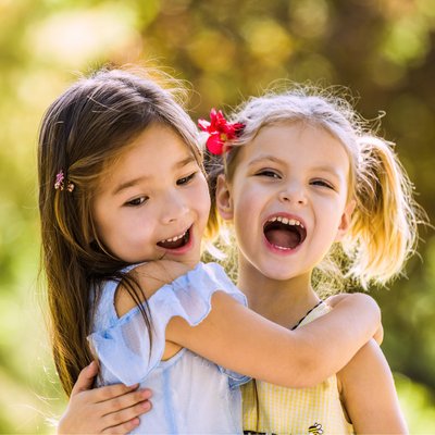 zwei Mädchen umarmen sich und lachen 