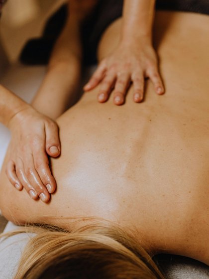 Frau auf einer Liege bekommt eine Rückenmassage